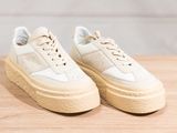 a pair of white sneakers sitting on top of a wooden table