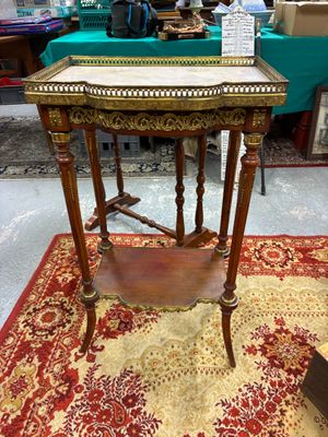 une table ancienne en bois posée sur un tapis rouge et or dans une pièce