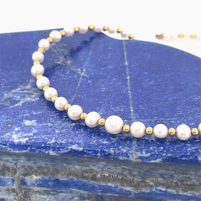 pearl and gold beaded necklace on a blue marble slab
