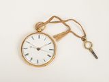 a gold pocket watch with a key attached to it
