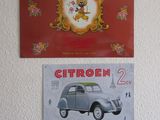 deux affiches accrochées au mur, au-dessus d'une voiture et d'une horloge