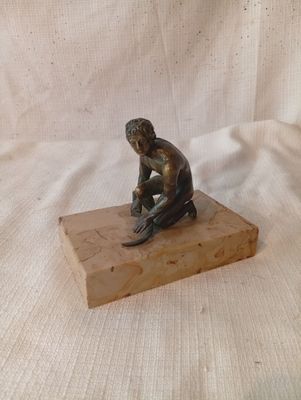statue représentant un homme assis sur un bloc, un couteau à la main
