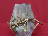 un vase orné d'une branche, posé sur une surface rouge