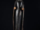 une statue en bois représentant une femme aux cheveux longs et coiffée d'un chapeau