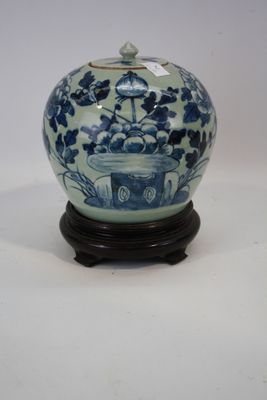 un vase bleu et blanc posé sur un socle, sur une surface blanche
