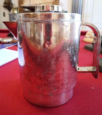 un pichet en argent posé sur une table rouge recouverte d'une nappe rouge