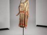une photo d'un mannequin portant une robe dorée avec une ceinture rouge