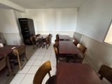 tables and chairs in a restaurant with a refrigerator in the background