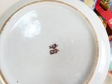 a white plate with a brown design on it sitting next to a stack of books