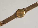 a close up of a gold watch on a white surface