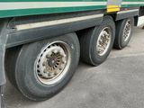 un semi-remorque vert avec un pneu crevé, garé sur le bord de la route