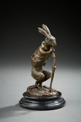 a bronze statue of a rabbit holding a stick on top of a wooden base