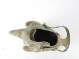 a small bronze object on a white surface with a white background