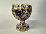 a blue and gold vase sitting on a white surface