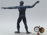 statue of a man with arms outstretched and a pocket watch on a table