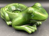 a green frog shaped ashtray sitting on a table