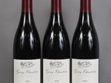 three bottles of red wine are lined up on a table