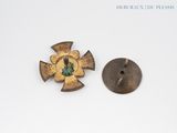 two pieces of metal with a cross and a green stone on them