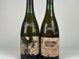 deux bouteilles de vin posées l'une à côté de l'autre sur une surface blanche