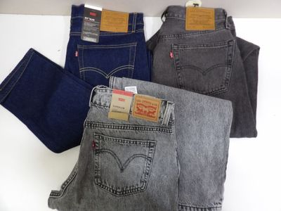 three pairs of levi ' s jeans sitting on top of each other