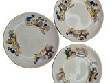 three plates with cartoon characters on them sitting on a white surface