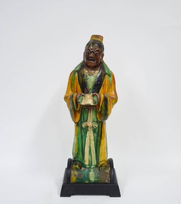 une statue verte et jaune représentant un homme tenant un livre