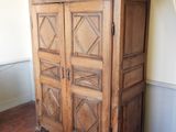 une grande armoire en bois sur laquelle sont posés de nombreux vêtements