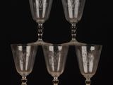 four wine glasses sitting on top of a wooden table next to each other
