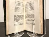 an open book sitting on top of a table next to a glass candle holder