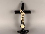 une croix noire accrochée au mur, sur laquelle est apposée une croix dorée