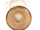 a glass vase with a brown base on a white surface