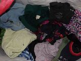 a pile of clothes on a bed with a hat on top of it