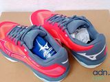 pair of grey and red running shoes with a blue bottle on top of a box