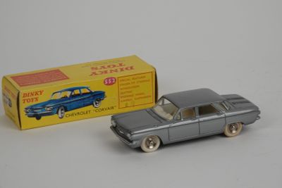 une vieille petite voiture et une boîte de jouets posées sur une surface blanche