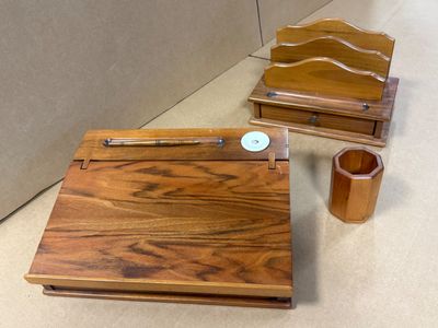 une boîte en bois contenant un stylo et un porte-stylo en bois, posée par terre