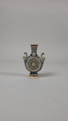 un vase bleu et blanc posé sur une surface blanche