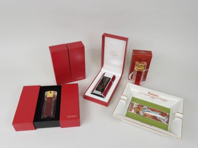 trois boîtes rouges contenant des parfums et un briquet, posés sur une surface blanche