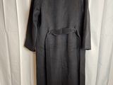 a black coat is hanging on a hanger on a white curtain