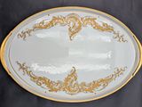 an oval platter with gold and white designs on a black background