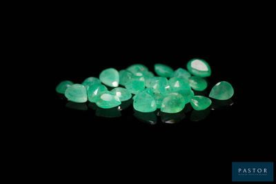 a close up of a bunch of green gems on a black surface