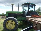 a tractor that is sitting in the grass by a trailer