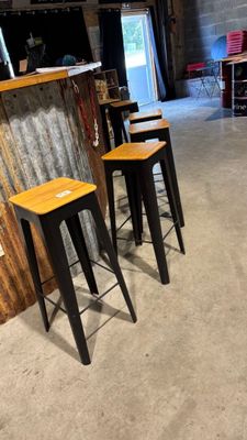 quatre tabourets placés devant un bar dans une pièce