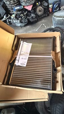 une boîte en carton contenant un radiateur, posée sur un tas de pneus