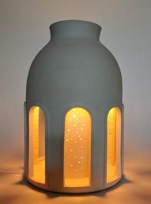 une lampe posée sur une table à côté d'un vase
