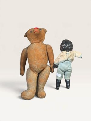un petit ours en peluche et une petite poupée, debout l'un à côté de l'autre
