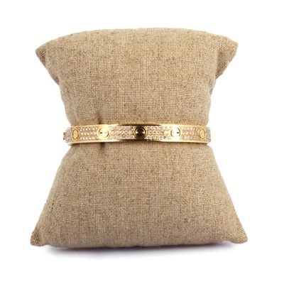 un gros plan sur un oreiller sur lequel repose un bracelet en or