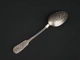 a silver spoon with a spoon handle sitting on a black surface