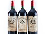 three bottles of red wine sitting next to each other on a white surface