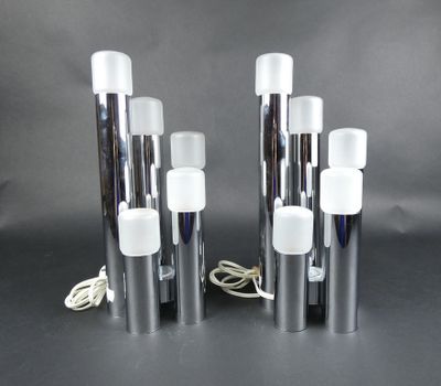trois lampes en verre argenté et blanc sont posées sur une surface noire