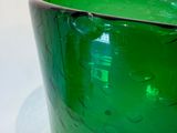 a green glass vase sitting on a white table